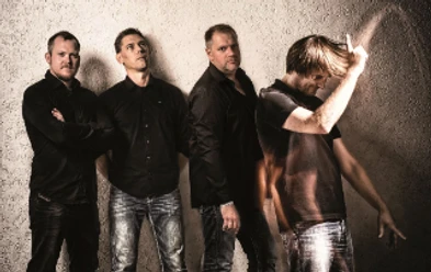 q-bic-live-funkband-im-filou.png Vierköpfige Funkband, alle in dunklen Hemden, posieren vor einer grauen Wand, einer tanzt freudig.