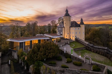 Schloss Homburg Schloss Homburg bei Sonnenuntergang, umgeben von Bäumen und einem modernen Anbau, im Herbst.