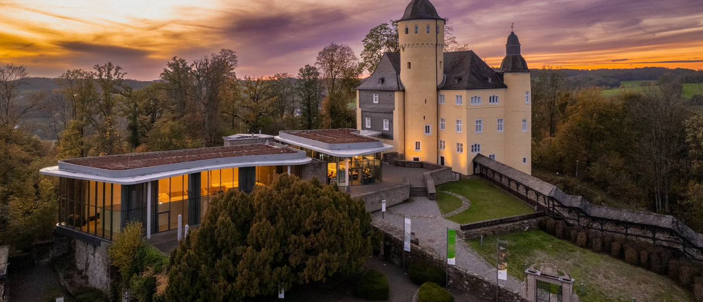 Schloss Homburg Schloss Homburg bei Sonnenuntergang, umgeben von Bäumen und einem modernen Anbau, im Herbst.