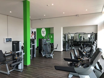 fitplus-wiefelstede-geraete Das Bild zeigt ein modernes Fitnessstudio mit verschiedenen Cardiogeräten, Hanteln und hellen Räumen.