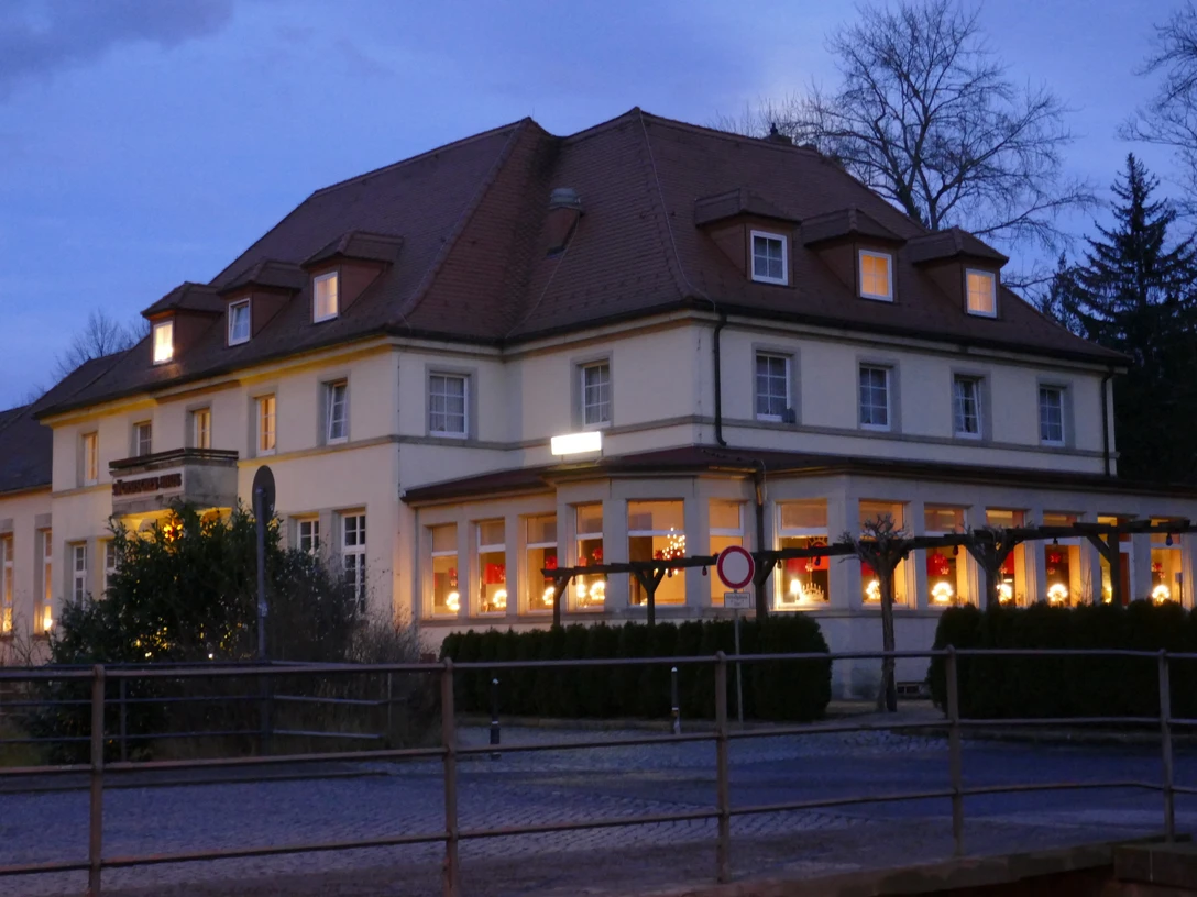Zeitgeist Sächsisches Haus.JPG Großes, beleuchtetes Gebäude bei Dämmerung, mit roten Vorhängen und Weihnachtsdekoration in den Fenstern, umgeben von Bäumen.Large, illuminated building at dusk, with red curtains and Christmas decorations in the windows, surrounded by trees.Velká osvětlená budova za soumraku s červenými závěsy a vánočními ozdobami v oknech, obklopená stromy.Duży, oświetlony budynek o zmierzchu, z czerwonymi zasłonami i świątecznymi dekoracjami w oknach, otoczony drzewami.Groot, verlicht gebouw in de schemering, met rode gordijnen en kerstversieringen in de ramen, omringd door bomen.Grande edificio illuminato al tramonto, con tende rosse e decorazioni natalizie alle finestre, circondato da alberi.