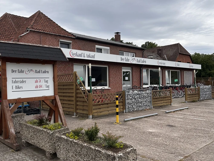 Fahrradverleih Mardorf am Steinhuder Meer Fahrradverleihstation mit E-Bikes in einem roten Backsteingebäude vor bewölktem Himmel.
