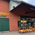 Hofladen Niemeyer Hofladen mit Backsteinfassade und grünem Holztor, dekoriert mit Kürbissen und Blumenschildern.