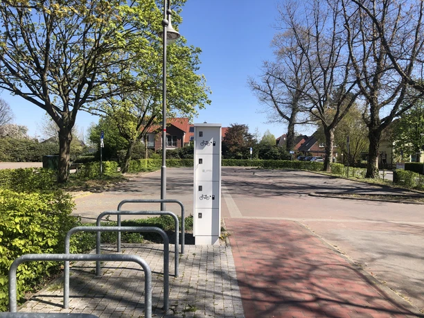 eBike Ladestation am Kögel-Willms-Platz Fahrradständer und Aufbewahrungsboxen an einem ruhigen Platz mit Bäumen und blauem Himmel
