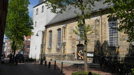 Evangelisch-reformierte Kirche in Lingen Sandstein-Kirchbau mit hohen Rundbogenfenstern und weißem Turm an einer ruhigen Straße in Lingen