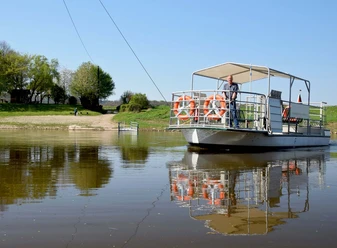 Fähre transportiert Menschen über die Weser, umgeben von sonnigem Grün und klarem Wasser.
