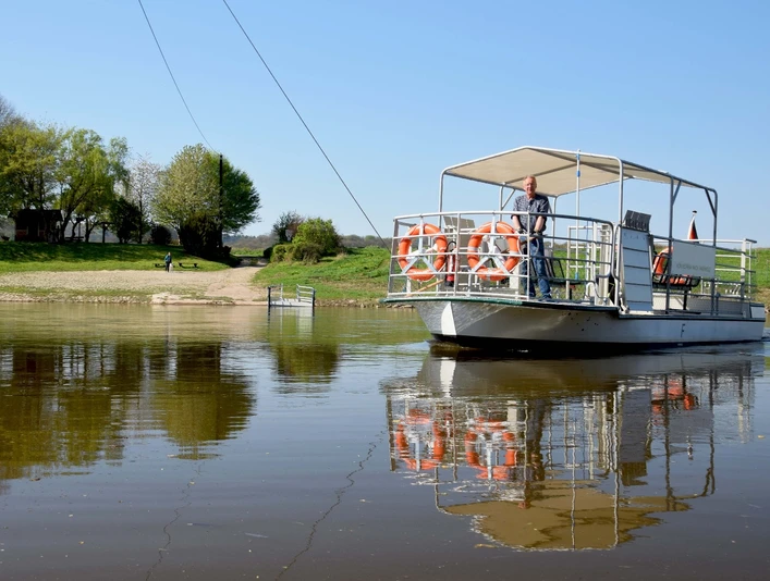 Fähre transportiert Menschen über die Weser, umgeben von sonnigem Grün und klarem Wasser.