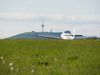 Flugplatz am Räuschenberg mit Köterberg im Hintergrund Ein kleines Flugzeug steht auf einer grünen Wiese mit dem bewaldeten Köterberg und einem Funkturm im Hintergrund.