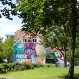 Paderborner Herzgraffiti im Mittleren Paderquellgebiet Graffitihäuserwand in Paderborn: Herzmural mit Landschaftsdetails zwischen Laubbäumen und Wiese.