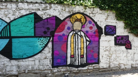 Graffiti des Heiligen Vinzenz von Paul an einer farbenfrohen Mauer mit geometrischen Mustern.