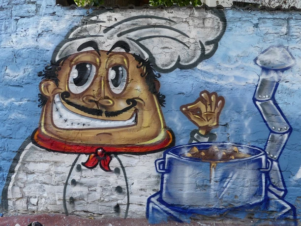 Graffiti "Suppenküche" an der Graffitimauer "Busdorfgalerie" Graffiti eines fröhlichen Kochs mit erhobenem Daumen neben einem dampfenden Suppentopf.