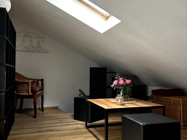 Gemütliche Dachgeschosswohnung mit hellen Holzböden, modernen Möbeln und Dachfenster, das Tageslicht hereinlässt.