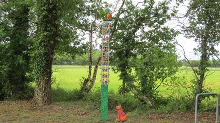 Lieblingsort Schutzhütte Apermarsch Die Schutzhütte Apermarsch ist umgeben von üppigem, grünem Laub und einer friedlichen, natürlichen Kulisse. Eine bunte, fantasievolle Skulptur aus Tieren ragt in die Höhe und zieht mit lebendigen Farben die Blicke auf sich. Künstlich gestaltete Figuren scheinen Geschichten zu erzählen, während im Hintergrund die Landschaft sanft ausrollt.