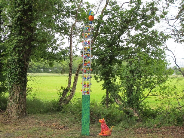 Lieblingsort Schutzhütte Apermarsch Die Schutzhütte Apermarsch ist umgeben von üppigem, grünem Laub und einer friedlichen, natürlichen Kulisse. Eine bunte, fantasievolle Skulptur aus Tieren ragt in die Höhe und zieht mit lebendigen Farben die Blicke auf sich. Künstlich gestaltete Figuren scheinen Geschichten zu erzählen, während im Hintergrund die Landschaft sanft ausrollt.