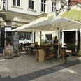 Das Bild zeigt den Außenbereich und Sitzmöglichkeiten des Mindener Feinkosthauses