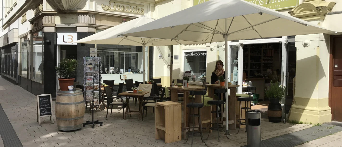 Das Bild zeigt den Außenbereich und Sitzmöglichkeiten des Mindener Feinkosthauses