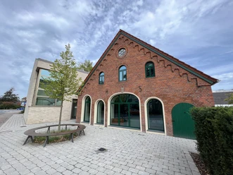 Kulturscheune Leeste Rot verklinkertes Kulturgebäude mit gewölbten Fenstern, Ziegeldach und angrenzendem modernen Anbau.