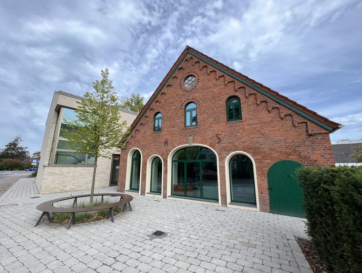 Kulturscheune Leeste Rot verklinkertes Kulturgebäude mit gewölbten Fenstern, Ziegeldach und angrenzendem modernen Anbau.