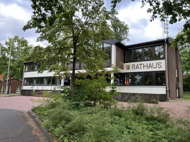 Backsteingebäude mit großen Fenstern, das Rathaus von Kirchlinteln, umgeben von Grünflächen.