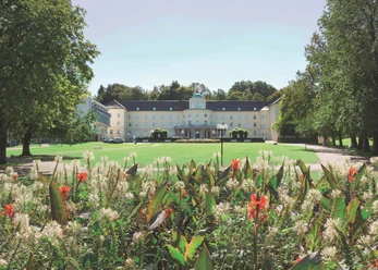 Park Klinik_Signature.jpg Die Parkklinik mit ihrer klassischen Architektur steht hinter bunten Blumen und Grünflächen.