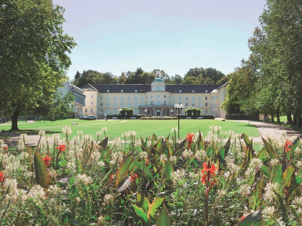Park Klinik_Signature.jpg Die Parkklinik mit ihrer klassischen Architektur steht hinter bunten Blumen und Grünflächen.