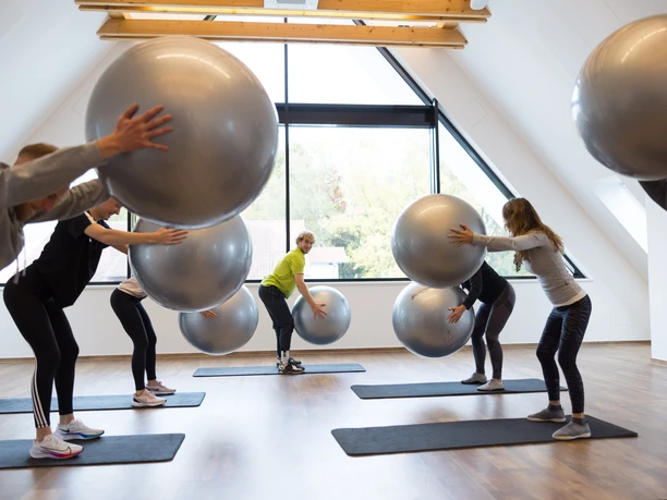 221021-FotoChristianSchwier-0790.jpg Menschen in einem Fitnessstudio trainieren mit großen Gymnastikbällen auf Matten vor einem Fenster.