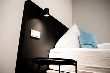 Modernes Schlafzimmer mit schlichter Dekoration; ein schlichtes Doppelbett mit weißen Bettwaren