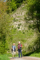 Wanderer direkt unter Eberschützer Klippen Zwei Wanderer mit Wanderstöcken spazieren auf einem Pfad, umgeben von grünen Eberschützer Klippen.