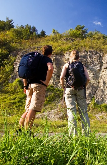 Wellenkalk am Prallhang Schwiemelkopf Zwei Wanderer betrachten eine beeindruckende Steilwand aus Wellenkalk unter einem klaren Himmel.