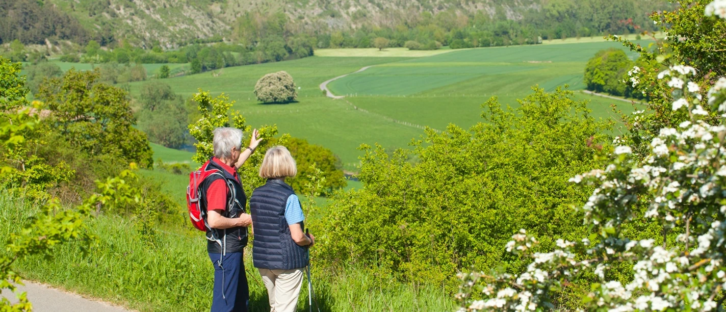 Wanderer bei Lamerden blicken auf Bunten Berg Eberschütz Zwei Wanderer betrachten eine weitläufige Landschaft mit grünen Feldern und bewaldeten Hügeln.