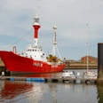 Das rot-weiße Feuerschiff liegt im Borkumer Hafen. Der Himmel ist grau bewölkt.The red and white fire ship is in the harbor of Borkum. The sky is gray and overcast.