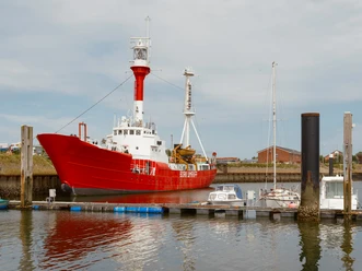 Nationalpark-Schiff Feuerschiff Borkumriff (2).jpg Das rot-weiße Feuerschiff liegt im Borkumer Hafen. Der Himmel ist grau bewölkt.