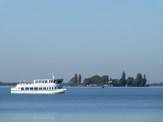 Het passagiersschip FGS Steinhude glijdt over een rustig meer, met het eiland Wilhelmstein op de achtergrond.