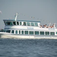 fahrgastschiff-steinhude-personenschifffahrt Weißes Passagierschiff der Steinhuder Personenschifffahrt auf dem Wasser, mit Menschen an Bord.
