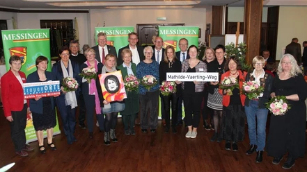 Gruppe von Menschen mit Blumen und Schildern bei der Ehrung für Mathilde Vaerting in Messingen