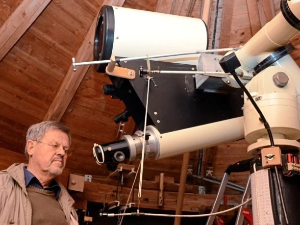 sternwarte Ein Mann betrachtet in hölzerner Kuppel ein großes Teleskop zur Himmelsbeobachtung.