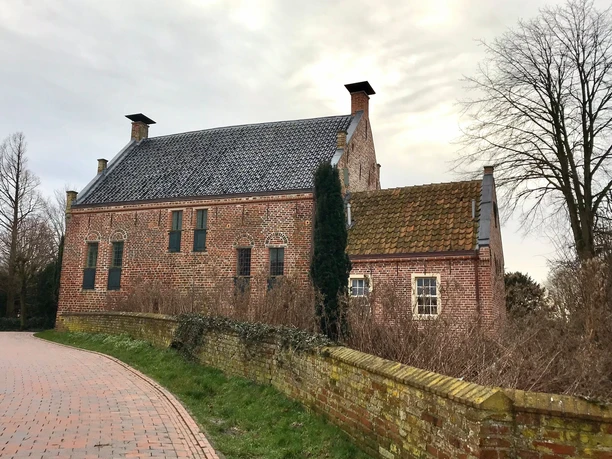 Steinhaus Greetsiel Historisches Backsteinhaus in Greetsiel mit Ziegeldach, Mauer und kahlen Bäumen