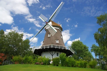 Achimer Windmühle Die Achimer Windmühle steht unter blauem Himmel, umgeben von Bäumen.