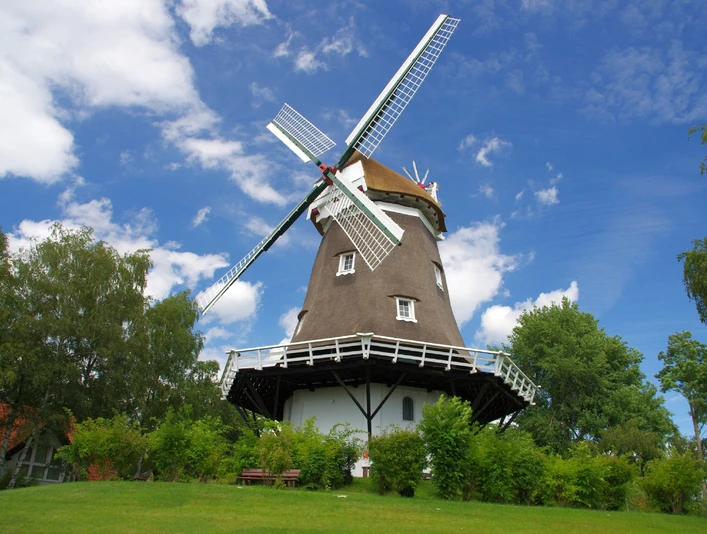 Achimer Windmühle Die Achimer Windmühle steht unter blauem Himmel, umgeben von Bäumen.