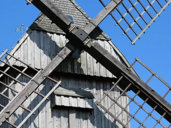 Ahrbecker Bockwindmühle Ahrbecker Bockwindmühle aus Holz mit Schindeldach, zentral im Bild, umrahmt von drehenden Flügeln.