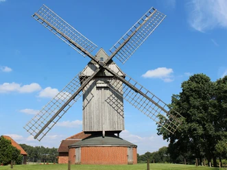 Die Ahrbecker Bockwindmühle mit ihren imposanten Flügeln vor strahlend blauem Himmel.