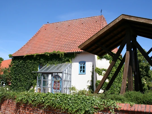 Kulturzentrum Alte Kapelle Haßbergen Das Bild zeigt die Alte Kapelle Haßbergen mit ihrem rot gedeckten Dach und von Efeu bewachsenen Wänden.