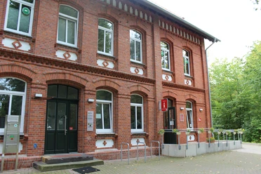 Tourist-Info Stolzenau Ziegelsteingebäude mit weißen Fensterrahmen, Fahrradständer vor dem Eingang und Tourist-Informationsschild.