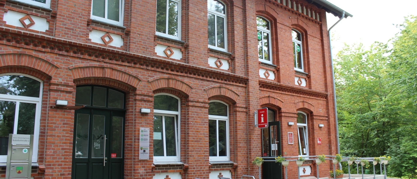 Tourist-Info Stolzenau Ziegelsteingebäude mit weißen Fensterrahmen, Fahrradständer vor dem Eingang und Tourist-Informationsschild.