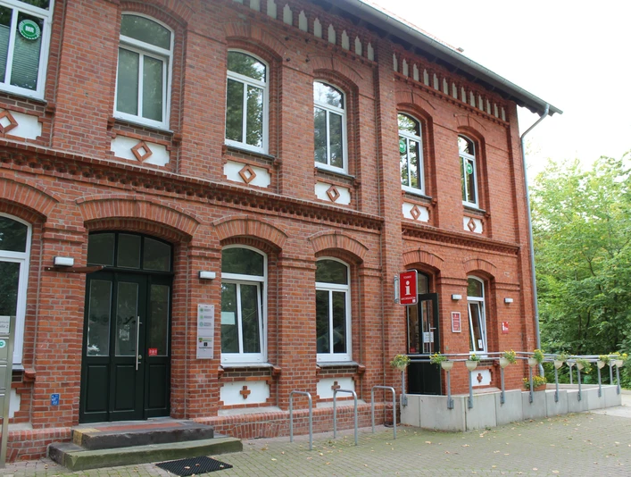 Tourist-Info Stolzenau Ziegelsteingebäude mit weißen Fensterrahmen, Fahrradständer vor dem Eingang und Tourist-Informationsschild.