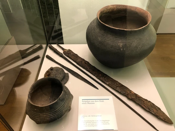 Eine Vitrine zeigt historische Werkzeuge und Keramikgefäße aus einem altsächsischen Männergrab.