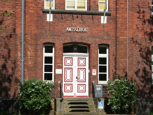 Backsteinfassade mit weißen Sprossenfenstern und kunstvoll verzierter Eingangstür des Amtsgerichts Achim.
