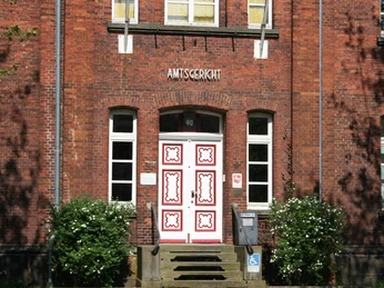 Amtsgericht Achim Backsteinfassade mit weißen Sprossenfenstern und kunstvoll verzierter Eingangstür des Amtsgerichts Achim.