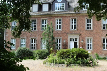 Amtshof 2 Bruchhausen-Vilsen Ein rotes Backsteingebäude mit vielen Fenstern, umgeben von Grün, bildet den Amtshof in Bruchhausen-Vilsen.