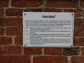 Infotafel aus Metall an roter Backsteinwand des Amtshofes Bruchhausen-Vilsen erklärt historische Details.